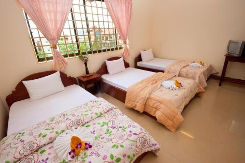 a room with three beds in a room at Okay Guesthouse Siem Reap in Siem Reap