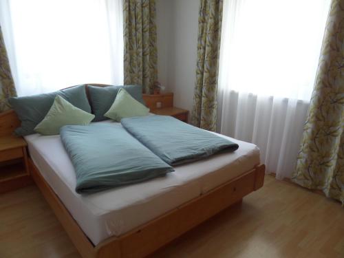 a bed with pillows on it in front of a window at Haus Regenbogen in Pertisau