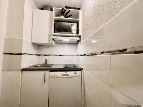 une petite cuisine avec des armoires blanches et un évier dans l'établissement Résidence Les Pentes - PENTES 18 MAE-0901, à La Plagne Tarentaise