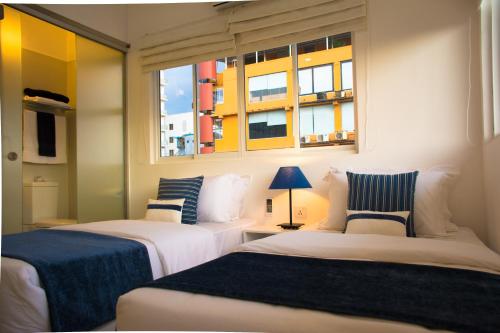 two beds in a room with two windows at The Residence in Colombo