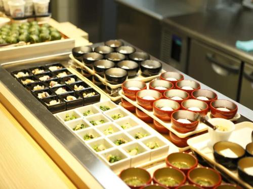 a buffet line with trays of different types of food at Dormy Inn Premium Wakayama Natural Hot Spring in Wakayama