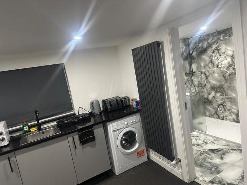 a laundry room with a washing machine and a tv at Modern Studio Flat In A Guest House In Basildon in Basildon