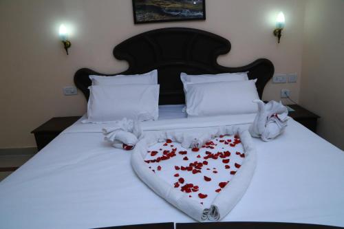 a bed with a white blanket with red hearts on it at Orison Residency Hotel in Kunnamkulam