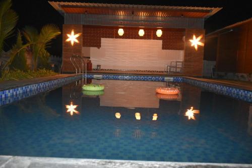 a swimming pool with lights in the water at night at Private pool with 3 bhk farm house Kuku farm stay # Moinabad in Venkatāpur