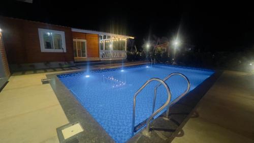 a large swimming pool at night with lights at Private pool with 3 bhk farm house Kuku farm stay # Moinabad in Venkatāpur