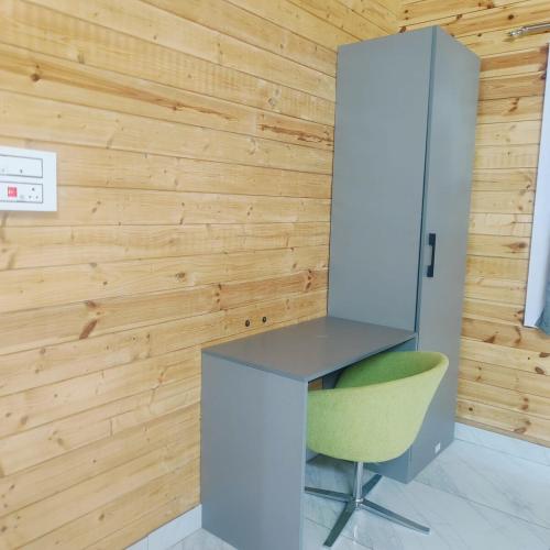 a desk and a green chair in a room with wooden walls at Private pool with 3 bhk farm house Kuku farm stay # Moinabad in Venkatāpur