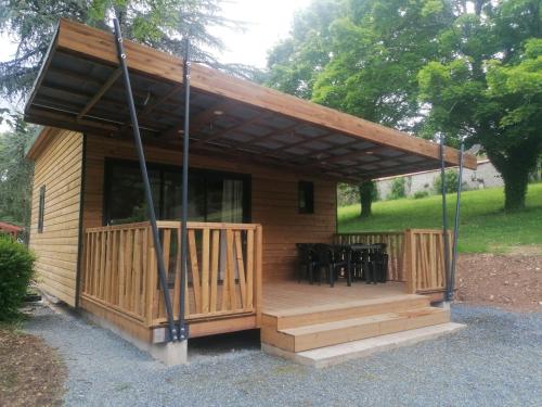 a wooden cabin with a deck with chairs at Camping L'oasis Du Berry in Saint-Gaultier