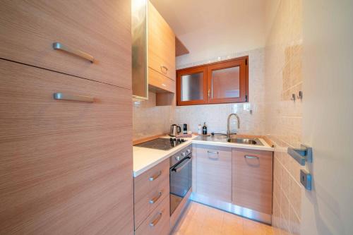 Il Nido Belmonte - Lakeview في Brezzo: مطبخ مع خزائن خشبية ومغسلة