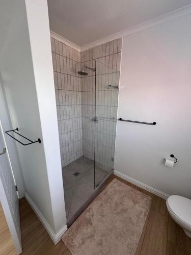a bathroom with a glass shower with a toilet at Sunset Shores in Lambertʼs Bay
