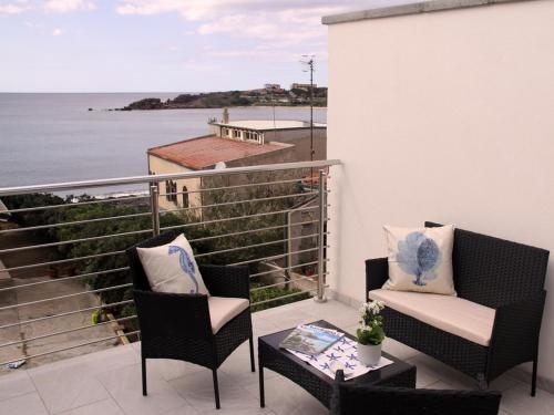 Un balcón con dos sillas y una mesa y el mar. en Panoramic Apartments, en Portoscuso