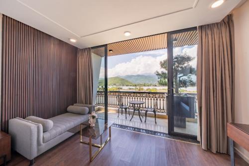 a living room with a couch and a tv and a balcony at Cami Riverside Resort Da Nang in Da Nang
