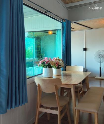 a dining room table and chairs with flowers on it at อากาศดีเขาค้อ akardd khaokho in Khao Kho