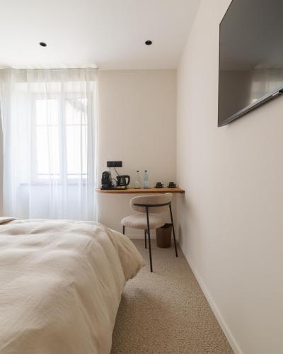 une chambre blanche avec un lit et une table dans l'établissement Ma maison, à Guémar