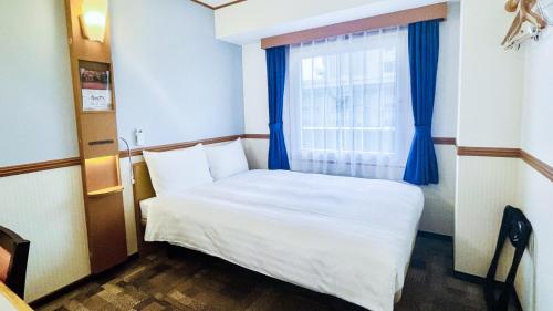 a small bedroom with a bed and a window at Toyoko Inn Hiroshima Heiwa-odori in Hiroshima