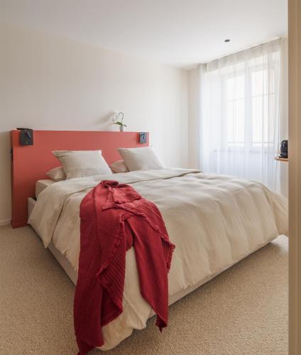 une chambre avec un grand lit avec une tête de lit rouge dans l'établissement Ma maison, à Guémar