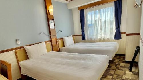 two beds in a room with a window at Toyoko Inn Hiroshima Heiwa-odori in Hiroshima