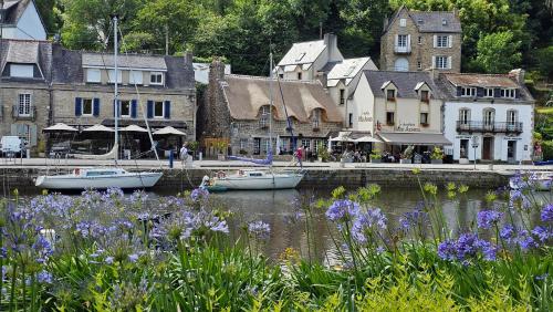 a town with boats in the water and purple flowers at La Chaumière Roz-Aven in Pont-Aven