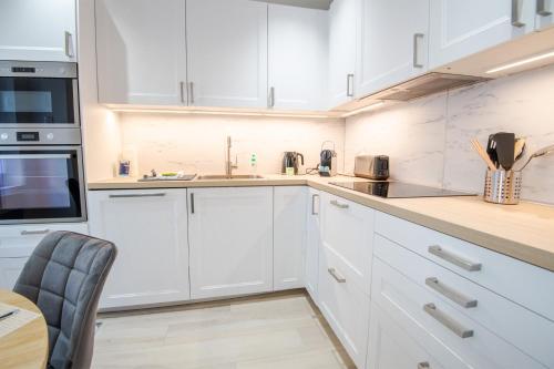 une cuisine avec des armoires blanches et une table dans l'établissement Le Havre Ligérien - Maison de charme pour 4personnes, à Amboise