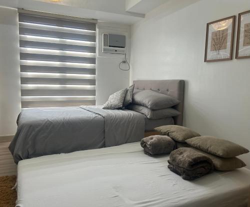 宿务Cozy Condo at Avida Tower 4, IT Park Cebu的客房设有两张床、一张沙发和一个窗口。