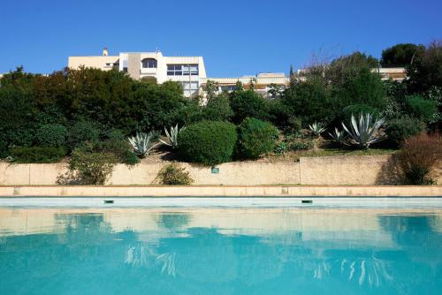 un grand bassin d'eau avec un bâtiment en arrière-plan dans l'établissement Saint-Mandrier - Vue Mer, Piscine & Sérénité, à Saint-Mandrier-sur-Mer