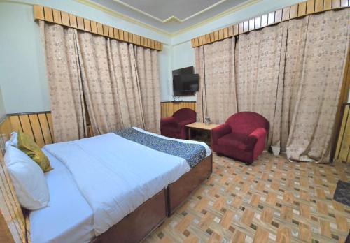 a bedroom with a bed and a chair and a television at Hotel Akashdeep in McLeod Ganj