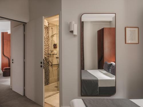 a mirror in a bedroom with a bed and a shower at Hôtel Belloy in Paris