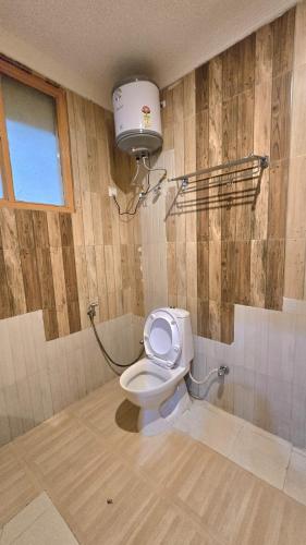 a bathroom with a toilet with a light on the wall at Hotel Akashdeep in McLeod Ganj