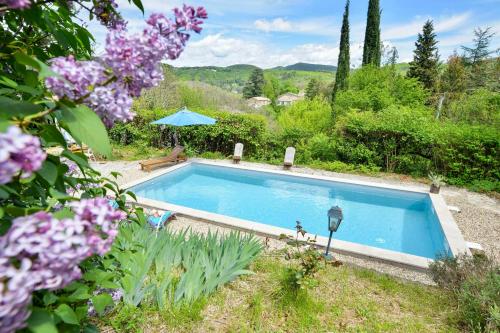 une piscine dans un jardin avec des fleurs violettes dans l'établissement Mas de Boissière - Chambres d'hôtes avec piscine et jacuzzi, à Cros