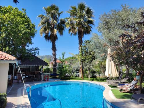 a swimming pool with palm trees in the background at Jasmin Apart Otel in Göcek