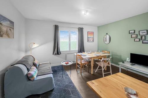 un salon avec un canapé et une table dans l'établissement Bright apartment - near the beach, à Merville-Franceville-Plage