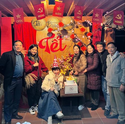 a group of people standing around a table with a cake at Pài Bjooc homestay in Làng Mán