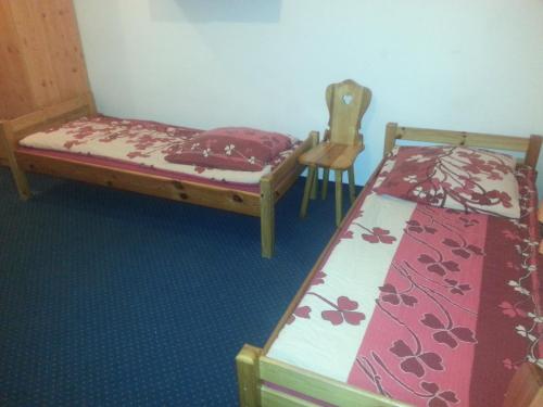 a bedroom with two beds and a chair at Arsenał Kwatery in Włocławek
