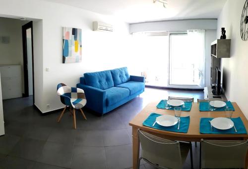un salon avec un canapé bleu et une table dans l'établissement Les Petites Alpes - Apt 5 Prs - 3 min des plages - climatisation, à Antibes