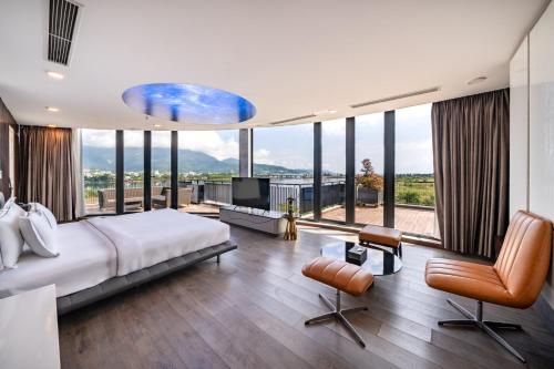 a bedroom with a large bed and large windows at Cami Riverside Resort Da Nang in Da Nang