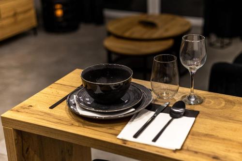 een houten tafel met een zwarte kom en twee wijnglazen bij Exclusive place with underground parking and terrace in Oświęcim