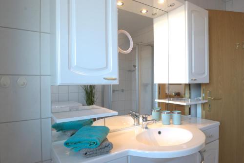 a white bathroom with a sink and a mirror at Ferienwohnung Claudia in Norden