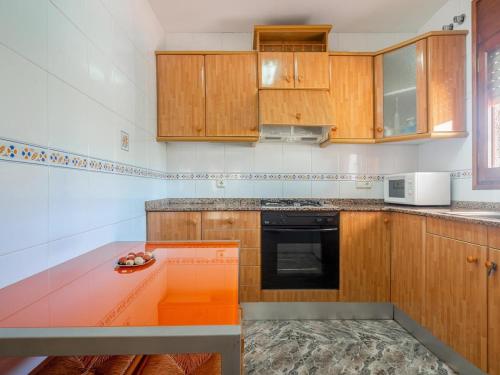 a kitchen with wooden cabinets and an orange counter top at Preciosa casa con un enorme jardín in El Vendrell