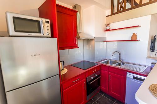 La cuisine est équipée de placards rouges et d'un réfrigérateur en acier inoxydable. dans l'établissement Vieil Antibes Duplex lumineux vue imprenable - Climatisé, à Antibes
