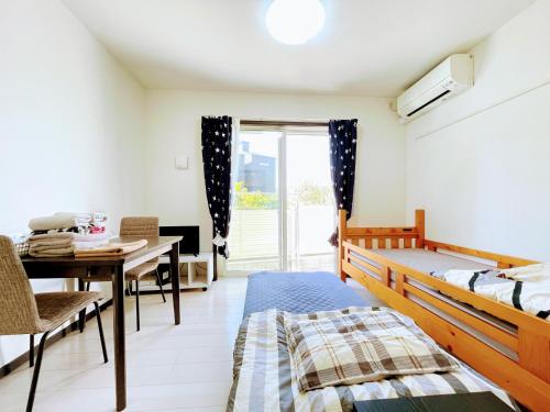 a bedroom with a bed and a table and a window at Credo Maison Kamakura102 in Kamakura