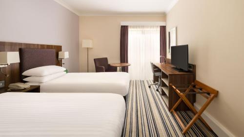 a hotel room with two beds and a television at Holiday Inn Rotherham-Sheffield M1,Jct.33 by IHG in Rotherham