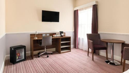 a hotel room with a desk and a television at Holiday Inn Rotherham-Sheffield M1,Jct.33 by IHG in Rotherham