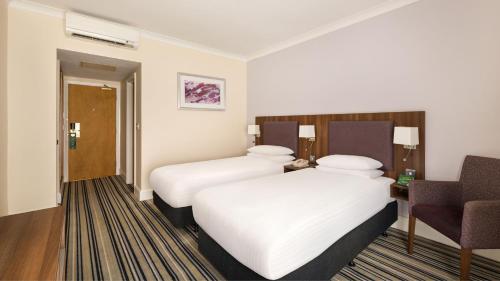 a hotel room with two beds and a chair at Holiday Inn Rotherham-Sheffield M1,Jct.33 by IHG in Rotherham