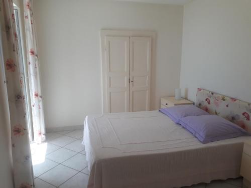 une chambre blanche avec un lit et une fenêtre dans l'établissement Maison de village avec terrasse, à Brando