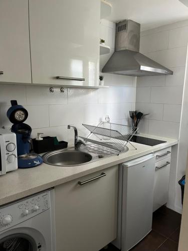 une cuisine blanche avec un évier et un lave-vaisselle dans l'établissement Joli studio cosy, à Marseille