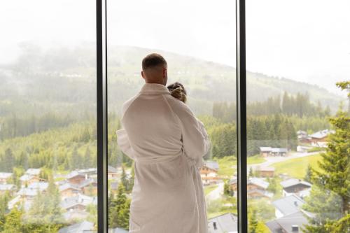 a man and a woman looking out of a window at Ursprung Panorama Hotel Königsleiten in Königsleiten