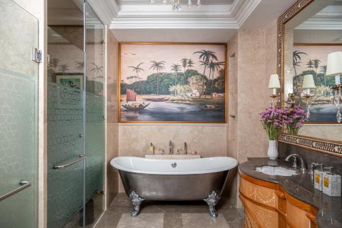 a bathroom with a tub and a painting of palm trees at Raffles Udaipur in Udaipur