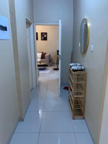 a hallway with a white floor and a mirror at Comfort at home in Gaborone