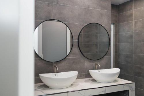 a bathroom with two sinks and two mirrors at Luma Signature Hotel in Seremban