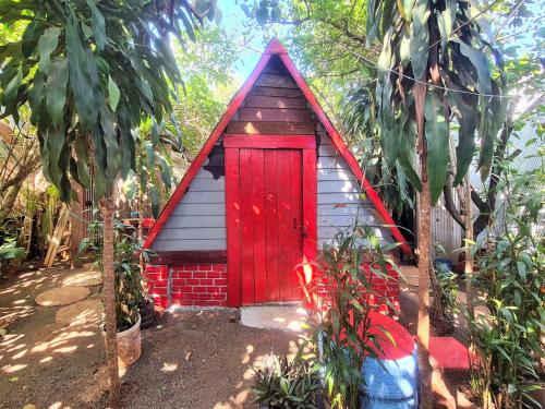 a small house with a red door in a garden at Ratanakiri Homestay & Jungle Trek in Banlung