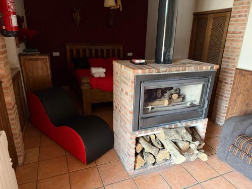 a living room with a fireplace and a red chair at La Casita Roja Del Arcoíris in Riópar